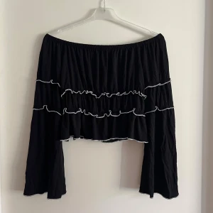 Off-shoulder topp - Svart, långärmad off-shoulder topp med volang! Oanvänd och i nyskick! Ärmarna är även utsvängda ner till. Storlek XS men tycker den sitter som S, har även stretchigt material i viskos! Det är bara att skriva om du har några funderingar! <3 