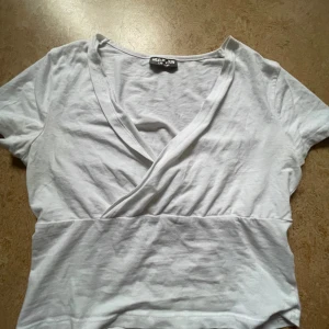 Vit omlottopp från Destiny - Snygg vit omlottopp från Destiny med korta ärmar och v-ringad. Har fläckar som knappt syns och som säkert går att tvätta❣️❣️priset kan diskuteras!!!