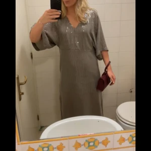 Glittrig långklänning med v-ringning - Använd en gång, den är brun/beige i färgen 