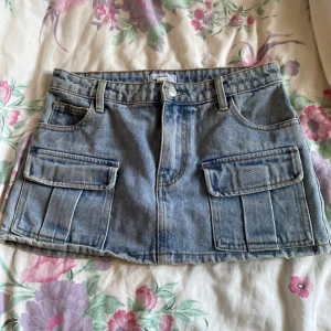 Blå söt jeanskjol från Forever 21 - Blå jeanskjol från Forever 21 i kort modell. Kjolen har två stora fickor framtill och dragkedja med knapp. Pris kan diskuteras❣️