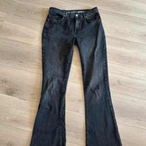 Svarta low flare jeans med bootcut - Snygga svarta jeans med låg midja och bootcut/flare passform. Klassisk femficksmodell med dragkedja och knapp framtill. Jeansen är i ett mjukt denimtyg och har en riktigt schysst siluett som ger retrovibbar.