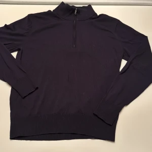 Mörkblå half zip stickad tröja Uniqlo - Mörkblå stickad tröja från Uniqlo i storlek XS. Tröjan har en hög krage med half zip-dragkedja och ribbade muddar vid ärmslut och nederkant. Perfekt för lager-på-lager och chill stil under kyliga dagar.