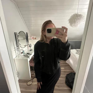 Grå/svart skinnjacka  - Svart/grå skinnjacka med cool croppad passform och dragkedja framtill. Jackan har quiltade paneler och en ficka med dragkedja på bröstet. Perfekt för dig som gillar en streetig stil och vill ha en jacka som sticker ut lite extra. Jag har klippt i axlarna inne i jackan för att få ut puffarna!