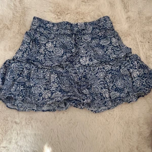Blåvit blommig volangkjol - Supersöt kort kjol från ZARA blått och vitt med blommigt mönster. Kjolen har volanger och resår i midjan för en bekväm passform. Perfekt för varma dagar och ger en fräsch och somrig vibe. Den här insydda short❣️🤗 Ser helt ny ut och har använt fåtal gånger 😆