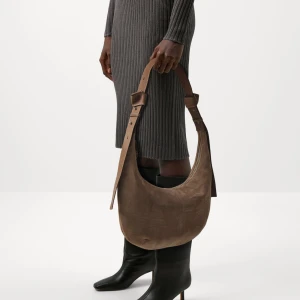 Beige axelväska i mocka (Lona bag) - Obs! Bilder från Zalando*** Säljer en snygg helt oanvänd beige axelväska i mjuk mocka med justerbart axelband i skinn. Väskan har en rundad form och stängs med dragkedja upptill. Perfekt för dig som vill ha en stilren och trendig accessoar till din outfit. Kan mötas i Sthlm vid garanterat köp 🤗