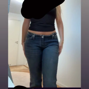 Mörkblå bootcut jeans med rå kant - Original pris 700kr. Säljer ett par mörkblå jeans med bootcut-modell och låg midja. (No waiste jeans från Nelly). Snygg tvätt och stretchigt denimtyg som sitter skönt. Perfekta för en trendig och avslappnad look. Säljer för att jag råkade köpa fel storlek använda 1 gång