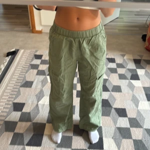 Gröna cargopants från H&M (Inte strukna) - Snygga ljusgröna cargopants från H&M med elastisk midja och flera praktiska fickor på sidorna. Byxorna har en loose passform och är tillverkade i mjuk bomull, perfekta för en chill och avslappnad stil.