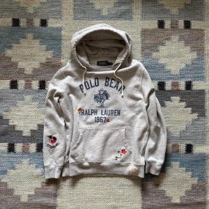 Grå hoodie Polo Bear Ralph Lauren -  Grå ralph Lauren hoodie med ikoniskt Polo Bear-tryck + broderade detaljer. Stor huva, känguruficka & tryck fram/bak. Skön passform, perfekt för chill dagar.  🧾 Nypris: 3300 kr ✅ Fint skick 