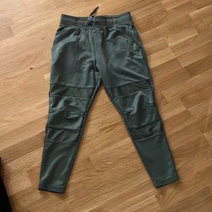 Gstar Gröna mjukisbyxor med snörning - Snygga gröna mjukisbyxor från Gstar med ribbade detaljer över knäna och snörning i midjan. Byxorna har smal passform, fickor fram och en bakficka med liten logga. Perfekta för chill eller träning.