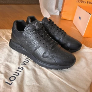 Louis Vuitton svarta sneakers i skinn - Passar 42/43Snygga vinter skor svarta Louis Vuitton sneakers i exklusivt skinn med präglad LV-logga och monogramdetaljer. Skorna har snörning, rund tå och platt sula. Perfekta för dig som vill ha en lyxig och stilren look med premiumkänsla. Originalkartong och dustbag medföljer.