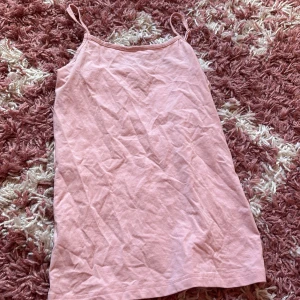 Ljusrosa linnetopp från Basic YMN - Säljer en ljusrosa linnetopp från Basic YMN med smala axelband och rak halsringning. Toppen är enkel och stilren, tillverkad i mjuk bomull som känns skön mot huden. Perfekt för varma dagar och enkel att matcha med jeans eller shorts.