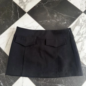 Svart kortkjol med fickdetaljer - Stilren svart kjol med en rak passform. 