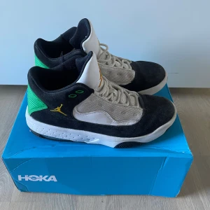 Jordan sneakers svart/vit/grön - Snygga Jordan sneakers med svart mocka, vita meshpaneler och gröna detaljer på hälen. Gula broderade loggor och texten 'JORDAN' bak. Skorna har snörning och en platt sula med svart och vit färg. Perfekta för dig som gillar streetstyle och sportig look. | Släng iväg en signal vid funderingar så svarar jag snabbt. |