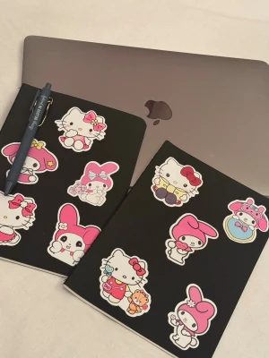 Svart anteckningsbok med Sanrio-stickers och ny penna med pennhållare - Säljer en svart anteckningsbok dekorerad med färgglada Hello Kitty och My Melody-stickers. Perfekt för skolarbete, dagbok eller kreativa idéer. Boken har mjukt omslag och är i smidigt format som är lätt att ta med sig i väskan.
