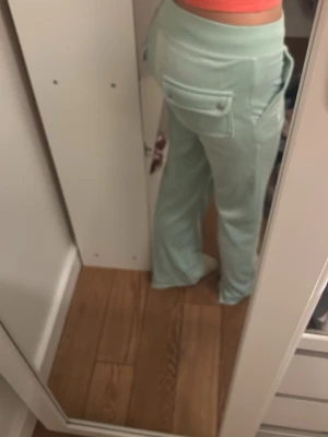 Mintgröna mjukisbyxor från Juicy Couture - Säljer ett par mintgröna mjukisbyxor från Juicy Couture med klassisk broderad logga på bakfickan. Byxorna har raka ben, bred resår i midjan och stora fickor bak. Supermjuka och perfekta för chill dagar.