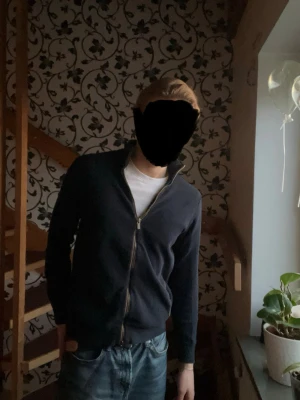 Mörkblå ziptröja Massimo dutti  - Mörkblå stickad ziptröja från Massimo Dutti med hög krage och hel dragkedja framtill. Tröjan har en klassisk, stilren design och är tillverkad i ett mjukt, strukturerat material som passar perfekt till jeans eller chinos.