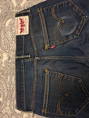 LEVIŚ 519 - Säljer ett par klassiska mörkblå jeans från Levi's med raka ben och snygga detaljer på bakfickorna.  STORLEK 32/32. Bara höra av dig vid fråga. Byte kan vara intressant.