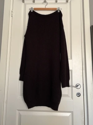 Svart stickad offshoulder klänning - Mysig svart stickad klänning med offshoulder-design och lång ärm. Klänningen har en rak, något loose passform och är perfekt för dig som gillar en avslappnad men ändå trendig stil. Passar bra till boots eller sneakers.