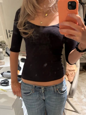 Svart urringad ribbad topp - Säljer en ljus svart ribbad topp med fyrkantig ringning och halvlånga ärmar. Toppen är tight i modellen och croppad, vilket ger en snygg och modern look. Perfekt att matcha med jeans eller kjol för en trendig outfit. Använd 1 gång från Zara