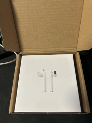 Apple AirPods med trådlöst laddningsetui - Säljer ett par vita Apple AirPods med trådlöst laddningsetui. Snygg och stilren design i plast, perfekt för dig som vill ha smidiga och trådlösa hörlurar till mobilen eller datorn. Kommer i originalförpackning.
