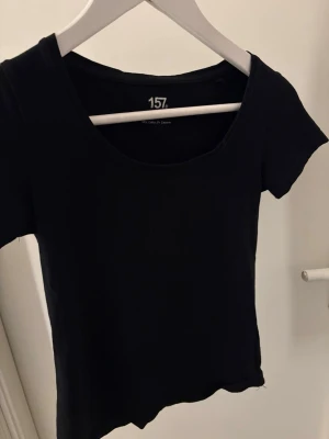T-shirt - En enkel och stilren svart topp från 157 i storlek XS. Toppen har korta ärmar, rundad halsringning och är gjord i mjuk bomull.