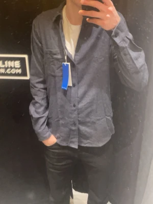 Mörkblå overshirt/skjorta från Samsøe Samsøe - Stilren mörkblå skjorta/overshirt från Samsøe Samsøe i mjuk bomull. Den passar perfekt nu till våren och även under sommaren. Perfekt att ha med en t shirt under! Använd under fåtal tillfällen. 