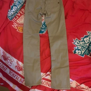 Beige chinos från Dondup - Snygga beige chinos från Dondup med klassisk rak passform och två bakfickor. Byxorna har diskreta sömmar och en stilren design, perfekta för en avslappnad men ändå uppklädd look. Tillverkade i mjukt bomullstyg för extra komfort. Dessa jeans är helt oanvända och nu ligger de ba o skräpar så väljer att sälja de