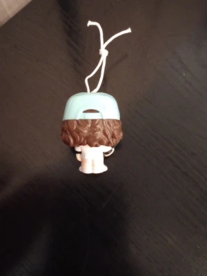 Stranger Things Funko Pop-figur hänge Dustin - Säljer en liten Dustin Funko Pop-figur från Stranger Things som hängsmycke. Figuren har brunt lockigt hår, vit och blå keps med texten 'Thinking Cap', vita kläder och en snodd för upphängning. Perfekt som dekoration eller till samlingen.