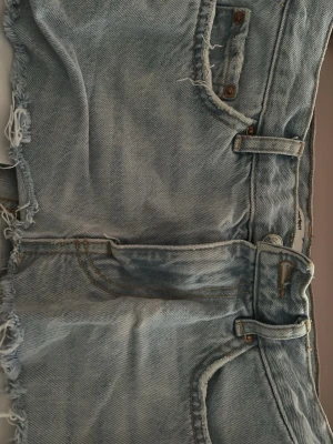 Ljusblå jeanskjol från gina - Snygga ljusblå jeanskjol med råa fransade kanter och klassiska fickor. Kjol har bälteshällor och dragkedja framtill. Perfekta för varma dagar och en avslappnad stil.