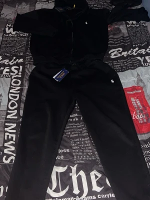 Svart hoodie och byxor från Polo Ralph Lauren - Hej, säljer en hel svart  polo Ralph Lauren set/ tracksuit, zip up tröjan är i storlek L men passar M och är i bra skick, byxorna är i storlek M och är ok skick, finns tecken på användning men inga hål eller fläckar eller liknande 