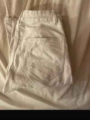 Vita jeans från Lindex - Säljer ett par vita jeans från Lindex med klassisk femficksdesign och raka ben. Jeansen har bälteshällor och knappgylf. Perfekta för en fräsch och stilren look. Materialet är denim i bomull. Low waist, storlek 170, men passar mig som har mellan 34 o 36 i storlek