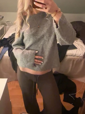 Grå stickad tröja - Mysig grå stickad tröja med avslappnad passform och rund halsringning. Tröjan har långa ärmar och ribbstickade muddar vid ärmslut och nederkant. Perfekt för lager-på-lager och chill dagar.