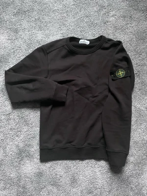 Svart sweatshirt från Stone Island - Mer bilder? Fråga bara ! Den är äkta! Riktigt snygg stone Island sweatshirt passar till allt. Kom och fråga några frågor om ni har!!!!!!!