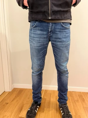 Blå slim fit dondup jeans med tvättade detaljer - Säljer ett par blå slim fit jeans med snygga tvättade detaljer och klassisk femficksmodell. Jeansen har normal midja och smal passform hela vägen ner. Materialet är stretchigt denim som ger skön komfort och bra rörlighet. Hål på baksidan, men lätt att laga! W32 L 32