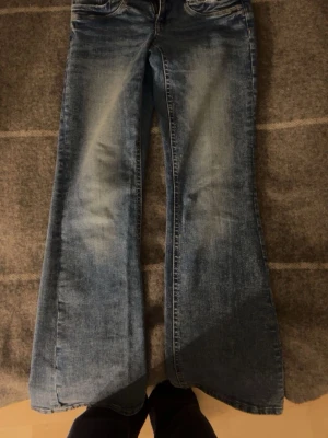 Blå utsvängda jeans - Säljer ett par blå lågmidjade bootcut jeans från gina tricot. Storlek 158