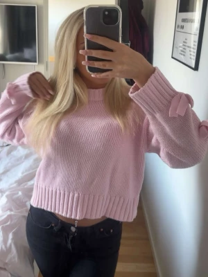 Rosa stickad tröja - Rosa stickad tröja med tre rosetter på varje arm. Storlek Xs, endast använd 2 gånger. 