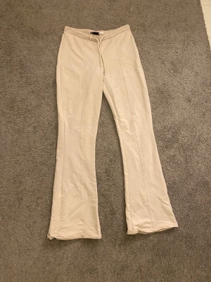 Beige mjukisbyxor 157 S - Beiga mjukisbyxor från 157 i storlek S med utsvängda-ben och snörning i midjan. Byxorna har en mjuk och skön bomullskänsla, raka sömmar framtill och en avslappnad passform. Perfekta för chill dagar eller när du vill vara extra comfy. Storlek S men passar i Xs oxå 