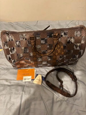 Louis Vuitton Keepall 50 Chess resväska - Unik Louis Vuitton Keepall 50 Chess resväska med schackrutigt mönster i brunt och transparent. Väskan har klassiska LV-monogramdetaljer, robusta handtag och justerbar axelrem. Materialet är en mix av skinn och transparent syntet, med dragkedja och LV-tag.
