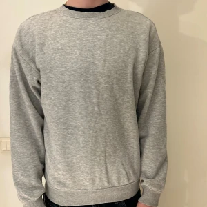 Grå Jack & Jones sweatshirt med rund hals - En enkel och stilren grå sweatshirt med rund hals och långa ärmar. Tröjan har ribbade muddar vid ärmslut och nederkant, vilket ger en snygg passform. Perfekt för dig som gillar en clean och avslappnad look.