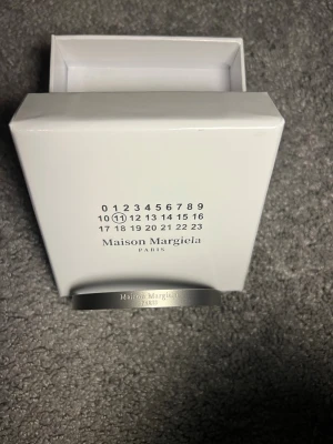 Maison Margiela silverarmband - Stilrent och minimalistiskt armband från Maison Margiela Paris, tillverkat i äkta 925 silver. Armbandet har en enkel, rak form med ingraverad logotyp på framsidan. Kommer med originalförpackning och är tillverkat i Italien. Perfekt för dig som gillar diskret lyx.