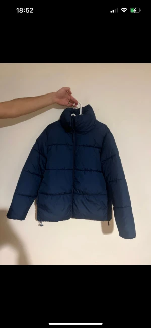 Mörkblå pufferjacka från Cubus - Säljer en mörkblå pufferjacka från Cubus i storlek M. Jackan har hög krage, dragkedja framtill och justerbar nederkant med snörning. Perfekt för kalla dagar och har en clean, stilren look som funkar till de flesta outfits.