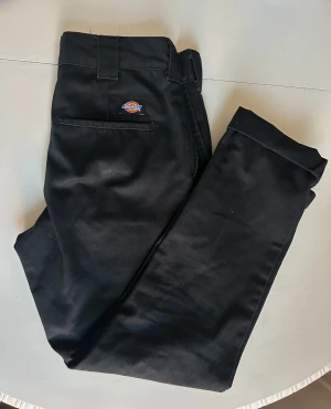 Svarta slim fit byxor från Dickies - Ett par svarta Dickies byxor med slim fit passform. Byxorna har fickor på sidorna och bak, storlek W30/L32