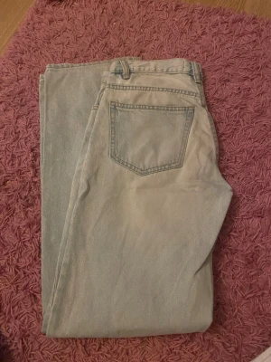 Ljusblå straight jeans från Gina tricot - Ett par ljusblåa jeans från Gina, storlek 34, har ett litet hål på ena knäet (se bild) men i övrigt fina, dock så finns det en liten smutsfläck på fickan bak, men går nog bort i tvätten! 
