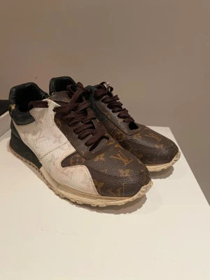 Louis Vuitton Rockrunner sneakers brun/vit - Säljer ett par Louis Vuitton Rockrunner sneakers med klassiskt monogrammönster i brunt och guld på tå och sidor, samt vita och svarta paneler. Skorna har rund tå, platt sula och bruna snören. Tillverkade i skinn med lyxig känsla och detaljerad design. Skorna är lite smutsiga men med en tvätt så svår det mesta. Bort. Skorna passar som 40-41 med det står 41 i skorna. Skriv vid funderingar-svarar så snabbt vi kan