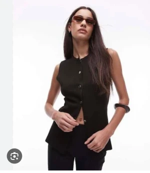 Ny! Zara Svart figurnära väst med knappar Stl s - Snygg svart väst med rund hals och knäppning framtill. Modellen är figurnära med en lätt utsvängd nederkant som ger en cool siluett. Materialet är mjukt och stretchigt tack vare inslag av elastan. Perfekt att styla med jeans eller kjol för en trendig look. Zara. Endast provad 