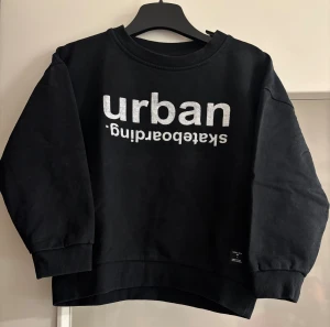 Svart sweatshirt Urban Skateboarding - Cool svart sweatshirt från Urban. Tröjan har rund hals, ribbade muddar och en loose passform som ger en avslappnad vibe. 