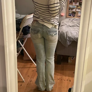 Ljusblå jeans från true religion - Lågmidjade bootcut jeans från true religion som inte säljs längrr. Jeansen är i storlek w.25 men jag har sytt in resår i midjan så att de sitter som w.24. De är väldigt stretchiga och har lite slitningar på benen. Jag är fortfarande osäker på om jag vill sälja dessa jeans, därav priset❣️❣️