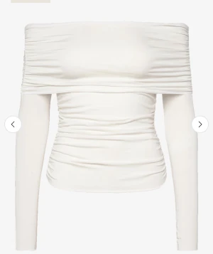 Vit offshoulder topp med långa ärmar - Säljer en stilren vit offshoulder topp med långa ärmar och snygga rynkade detaljer. Toppen är figurnära och har en modern, croppad passform som framhäver axlarna. Perfekt för dig som vill ha en trendig och enkel look.