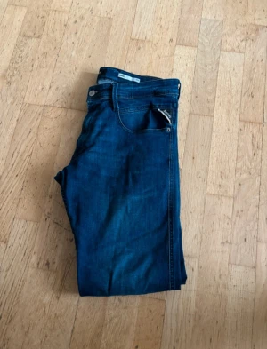 Blå Replay Anbass slim jeans W33 L32 - Säljer ett par snygga blå jeans från Replay, modell Anbass Slim Fit. Klassisk femficksdesign med dragkedja och knapp, tillverkade i mjukt jeanstyg. Perfekta för dig som gillar en smalare passform och stilren look.