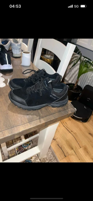Svarta sneakers från Exani strl 44 - Svarta sneakers från Exani i modellen Walker M. Skorna har en sportig design med snörning, rund tå och slitstark sula. Ovandelen är i syntet och mocka, vilket ger en snygg och stilren look. Perfekta för dig som gillar bekväma och funktionella skor.